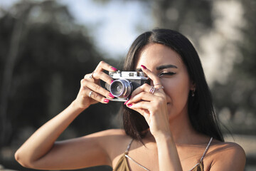 portrait of a young woman taking a picture with a vintage camera