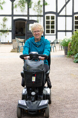 Happy smiling blond woman on mobility scooter , enjoying the freedom it gives her to get out and about unaided, despite her disability.