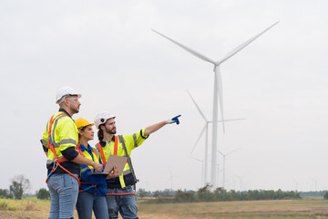 Group of male and female engineers discuss for maintenance of wind turbines at windmill field farm....