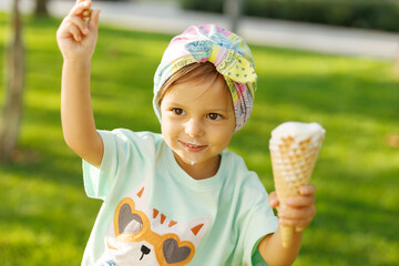 A little girl with emotions eats ice cream on the street in the park.