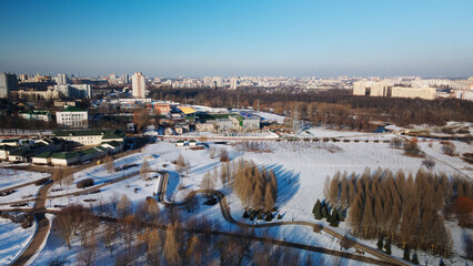 Obraz premium A winding bike path in a city park. City park in winter. Snow lies on the ground. Aerial photography.