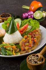 Deep fried fillet fish tilapia with onion chili, cucumber, tomato and steamed rice in white plate.
