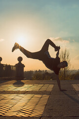 teenager boy with blue hair and sportswear dancing breakdace on the street. hip hop culture. street dancer doing pirouettes and stunts. © Alberto