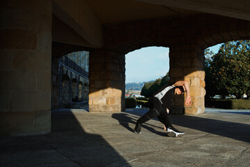 teenager boy with blue hair and sportswear dancing breakdace on the street. hip hop culture. street dancer doing pirouettes and stunts. © Alberto