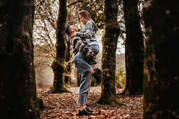 Obraz premium Couple in an autumn park, with the woman having jumped into the man's arms and him holding her securely