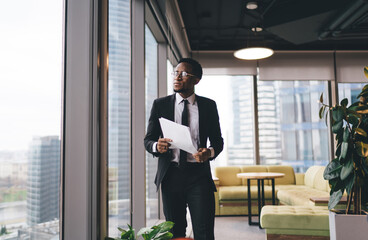 Fototapeta premium Serious black businessman with papers in office