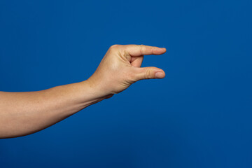 Male caucasian hand gesture of showing the small size with two fingers, isolated over the blue background