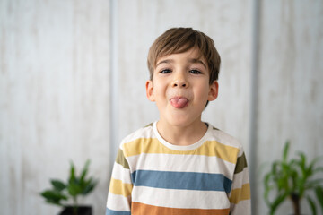 portrait of caucasian boy six years old protrude tongue at home