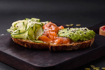 Delicious brown bread toast with salmon, avocado, cucumber and sesame seeds