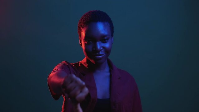 Positive feedback. Like gesture. Encouragement support. Red blue neon color light pleased woman recommending with thumb up isolated on dark night gif loop boomerang animation.