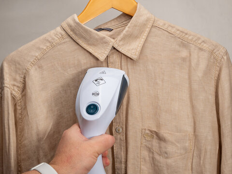 In hand Steamer for clothes. A shirt is ironed with a portable iron. Iron for ironing clothes.