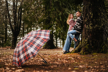 Couple standing near a tree with a patterned umbrella placed in the foreground