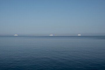 Luxury motor yachts on the horizon of calm sea