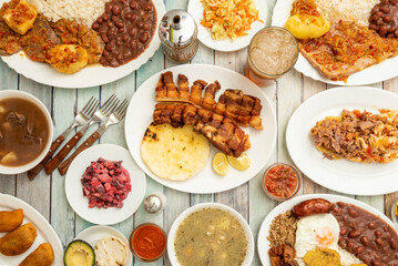 Colombian food dishes set with stews with legumes, chorizos, fried eggs, cooked white rice and arepas