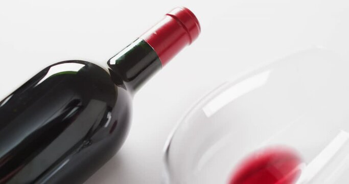 Red wine bottle, empty glass, cork and corkscrew lying on white surface with copy space