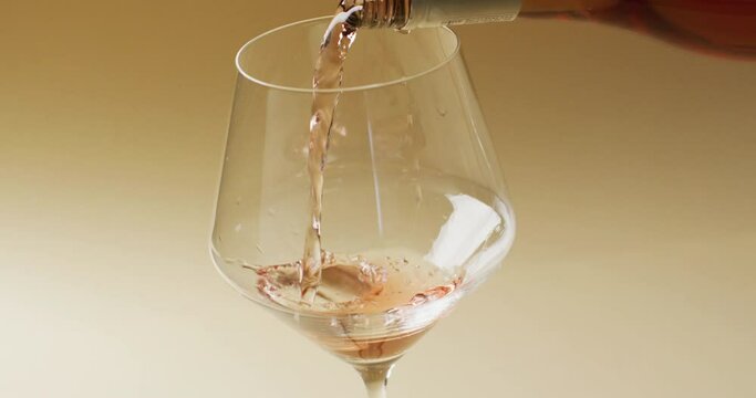 White wine pouring into glass over yellow background with copy space