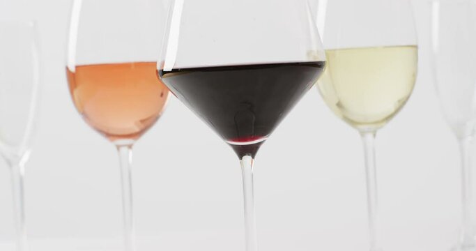 Diverse types of wines in glasses on white surface with copy space