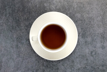 Cup of black hot tea on a gray background. Top view.