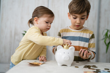 Siblings boy and girl small caucasian child brother and sister play at home with piggy bank saving money childhood investment insurance and finance concept copy space
