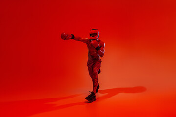 Fototapeta na wymiar Sporty man wearing head guard and boxing gloves practicing for fight on studio background