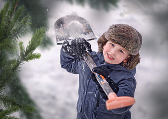 Boy with a shovel in the winter in fir branches