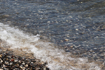 Pebble stones and sea waves. Background for beach vacation