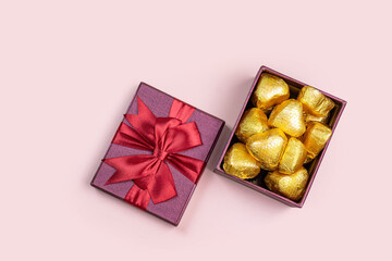 Variety of gifts and chocolates in the shape of a golden heart isolated pink background. Valentine's concept.