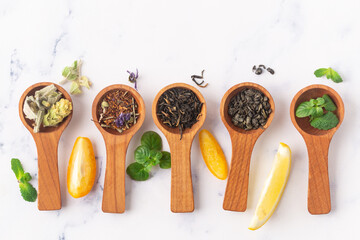 Various tea in wooden spoons. Black, green rooibus and herbal tea. Top view - obrazy, fototapety, plakaty
