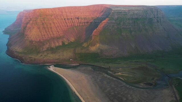 Aerial view of beautiful coastline with high cliffs at sunset facing the ocean at Tungurif Golden beach, Westfjord, Iceland.