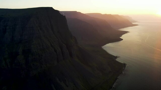 Aerial view of beautiful coastline with high cliffs at sunset facing the ocean at Tungurif Golden beach, Westfjord, Iceland.