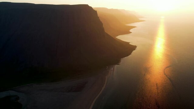 Aerial view of beautiful coastline with high cliffs at sunset facing the ocean at Tungurif Golden beach, Westfjord, Iceland.