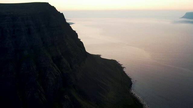Aerial view of beautiful coastline with high cliffs at sunset facing the ocean at Tungurif Golden beach, Westfjord, Iceland.