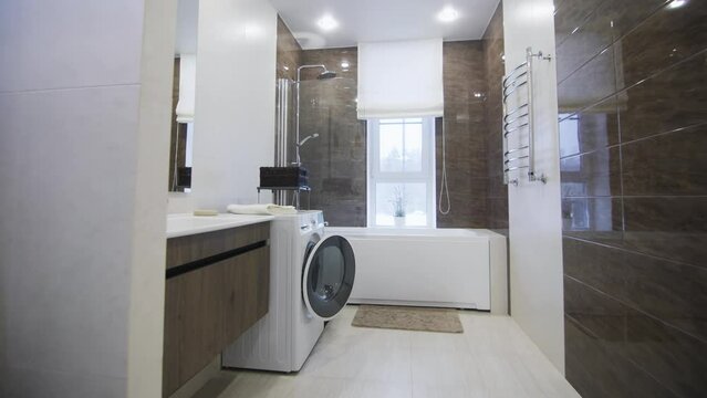 Contemporary bathroom equipped with necessary things in luxurious apartment. New washing machine and shower in spacious bathroom