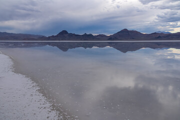 Obraz premium Scenic view of beautiful mountains reflecting in lake of Bonneville Salt Flats at sunset, Wendover, Western Utah, USA, America. Looking at summits of Silver Island Mountain range. Romantic atmosphere