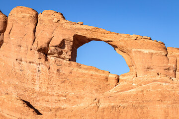 Natural sandstone ach on the side of a sheer cliff canyon in the desert of Arches National Park Utah.