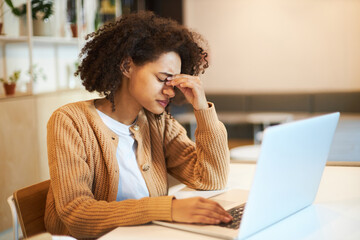 Overworked African American young woman freelancer entrepreneur or student sitting at a desk with...