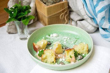 Spongy biscuit pieces with sugary powder and sliced mint leaves in a green plate on the table