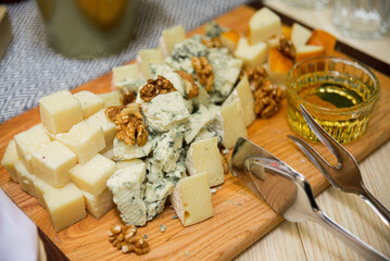 Cheese platter with different types of cheese, walnuts and honey