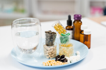 Many dietary supplements tablets and glass of water for daily pills intake on white background. Set of mulvitamin, amino acids, minerals and magnesium antistress, melatonin close-up.