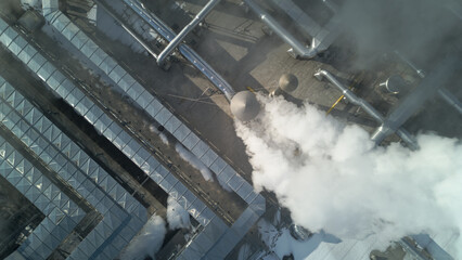 Dense white smoke and steam coming from a large manufacturing plant. Top down aerial footage.