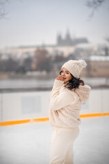 Beautiful girl having fun while skating at ice rink on Prague castle background, Czech republic