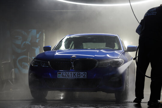 Minsk, Belarus February 7, 2023:  Close-up of the headlights of a modern luxury sports car with paint reflection after washing and waxing. Concept of car detailing and paint protection background.