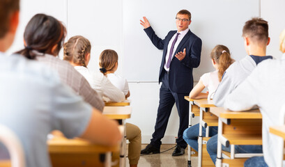 Portrait of male teacher lecturing to teenage students at auditorium