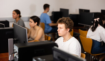 Concentrated schoolboy working with computers in classroom