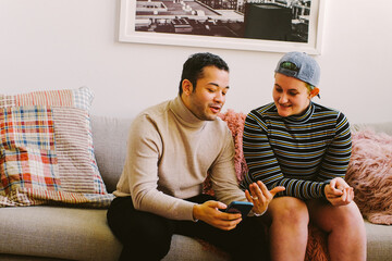 Trans couple sitting on couch with phone