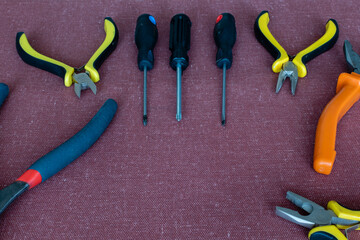 Set of tools of screwdrivers and wire cutters on dark fabric background