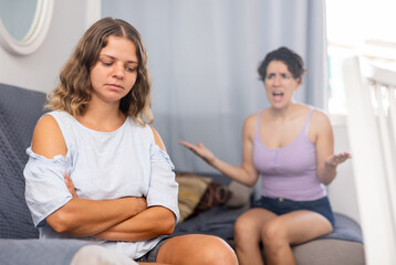 Offended stressed young woman ignoring her girlfriend arguing at home