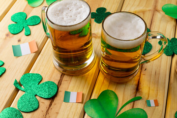 Image of beer glasses, clover and flag of ireland on wooden background