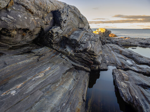 Striated metaphorphi rock layers and tidal pools make up the Pemaquid point near the Pemaquid lighthouse on th Maine Midcoast - Powered by Adobe