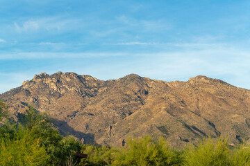 Towering and tall moutain range in the sonora desert in arizona with visible trees and plants on the base of hill